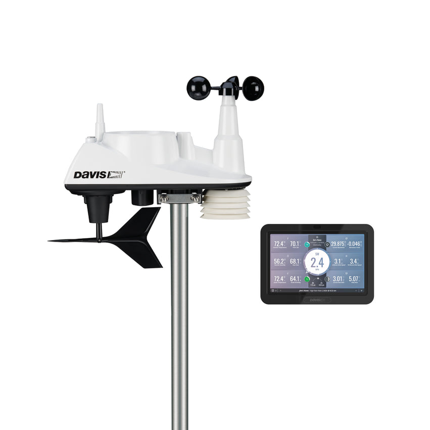White Davis all-in-one weather sensor suite on a metal pole with cup anemometer, wind vane, rain collector and radiation shield beside a colour display console